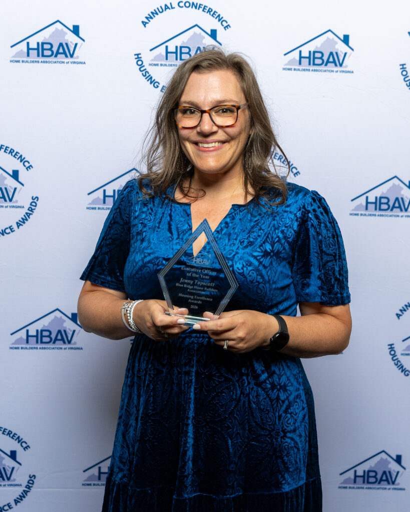 A woman smiling while holding a clear triangular award from HBAV.