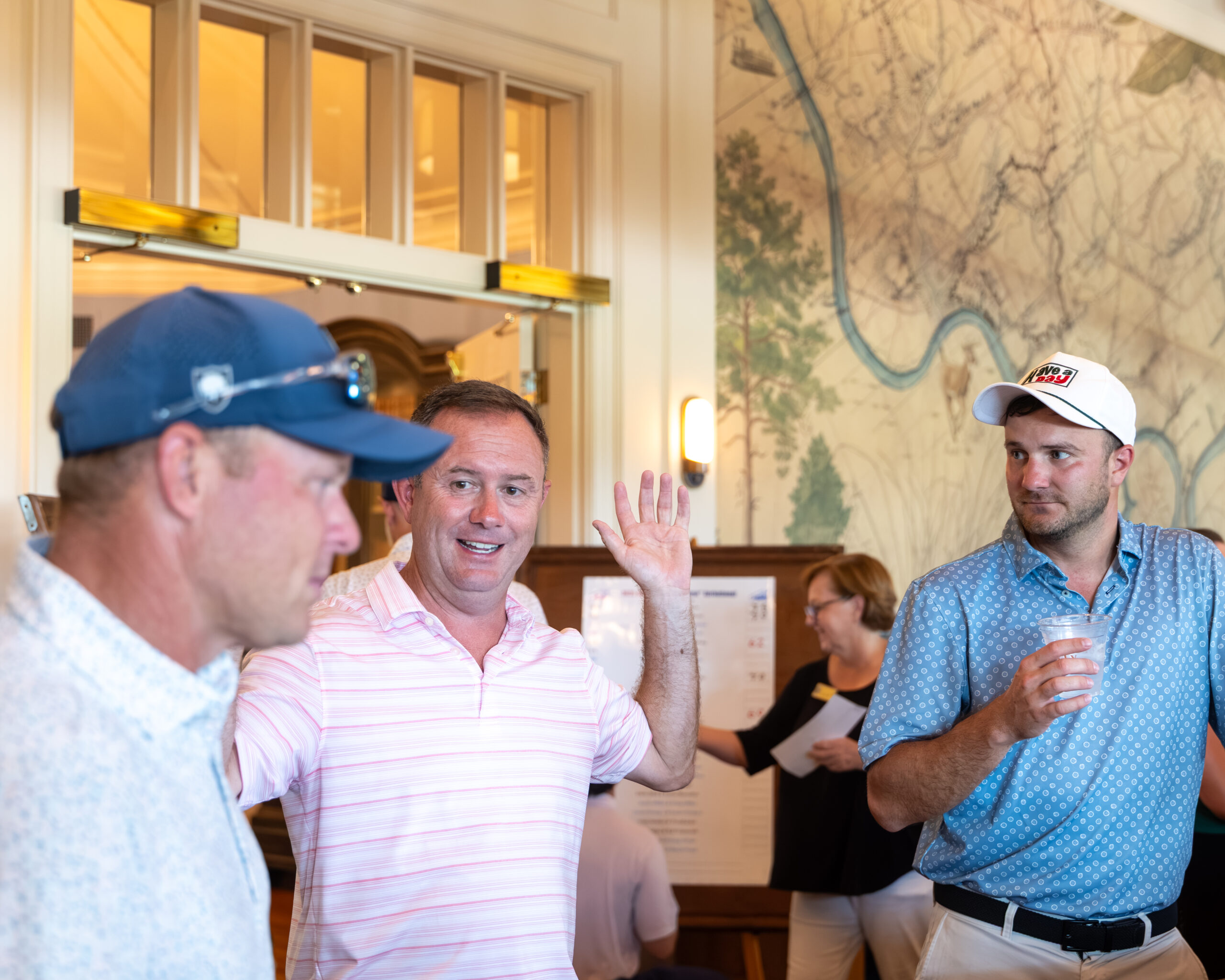 Three men in casual attire at an indoor golf club event.