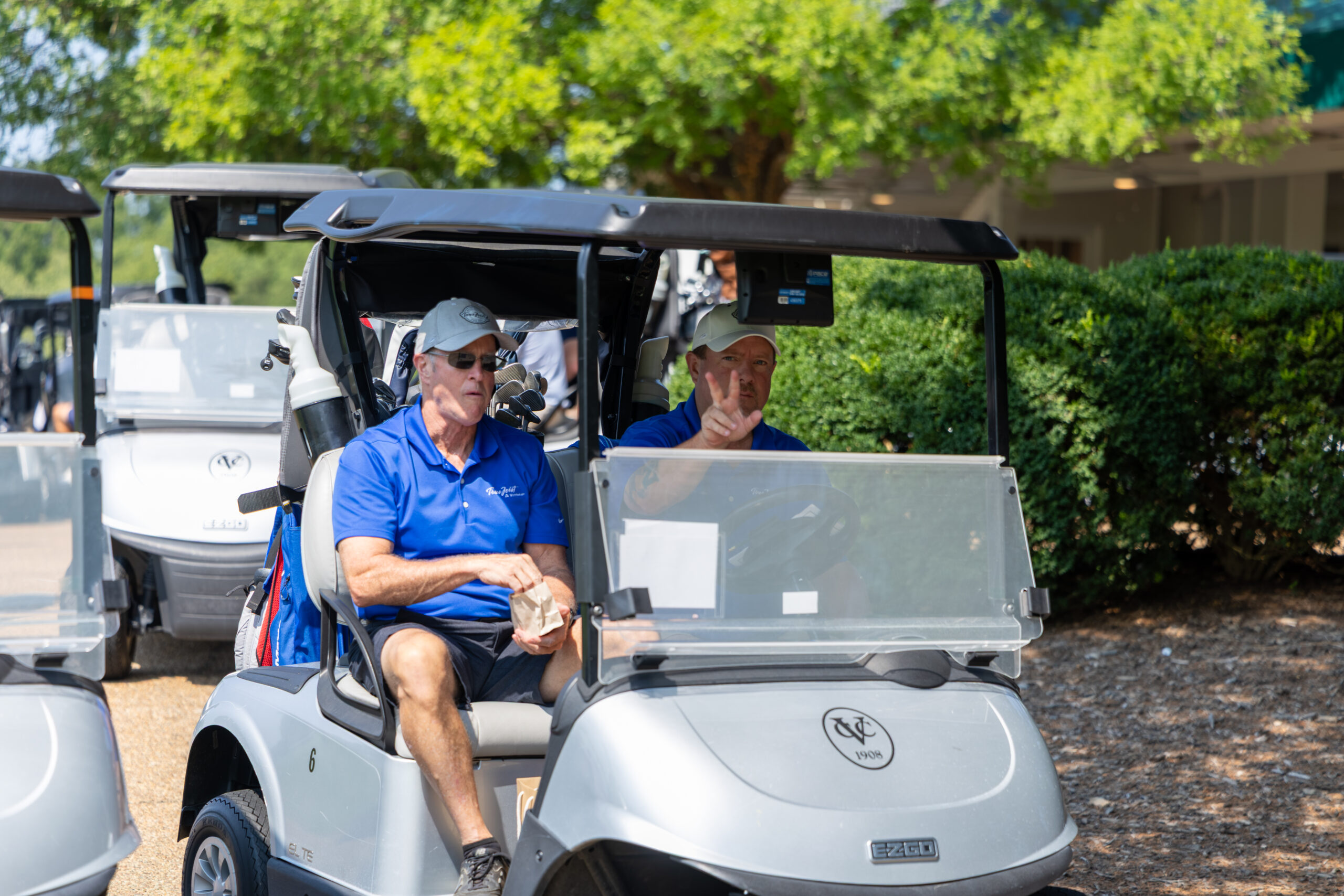 Two men on golf carts at a tournament.