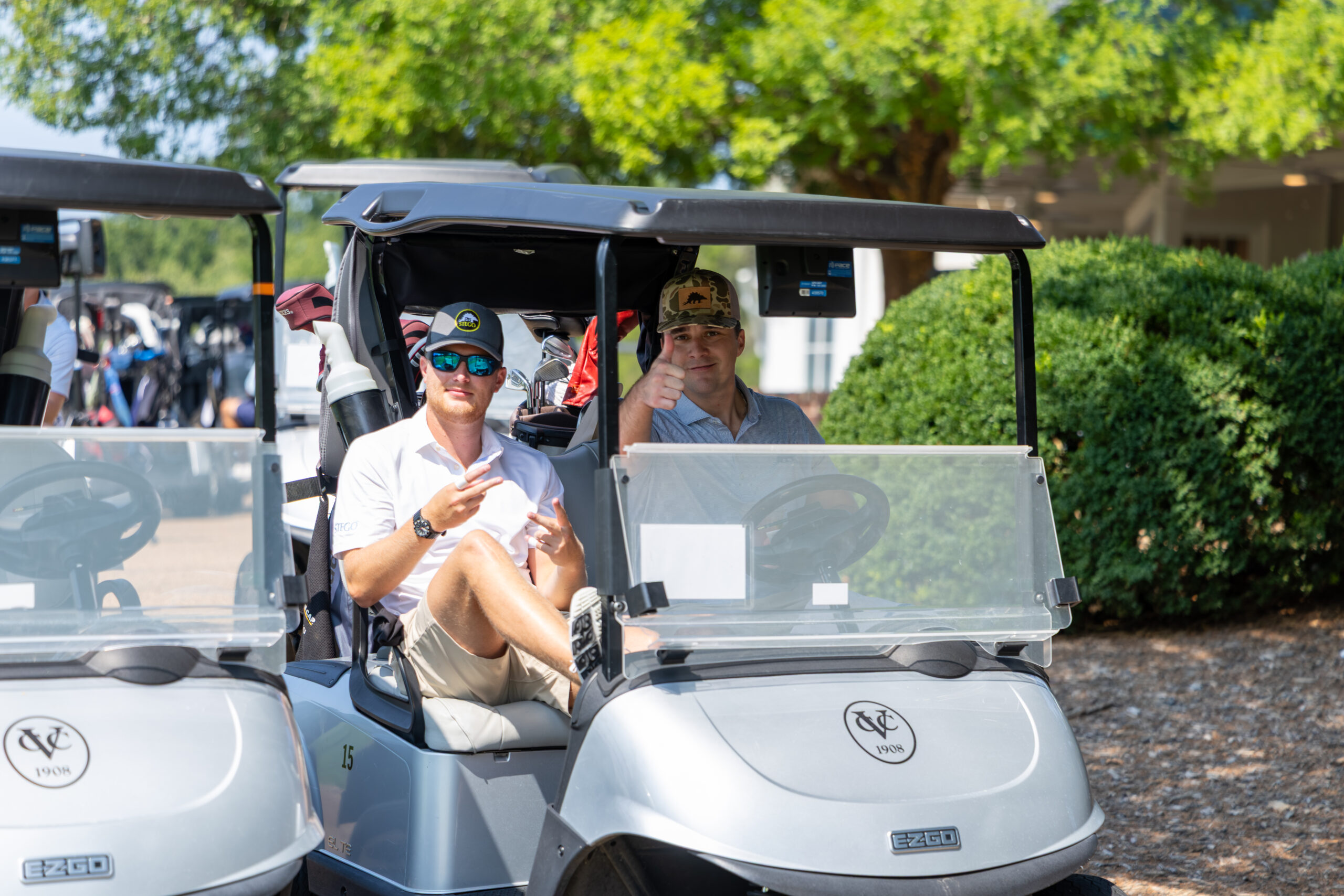 Two men sitting on golf carts at a tournament.