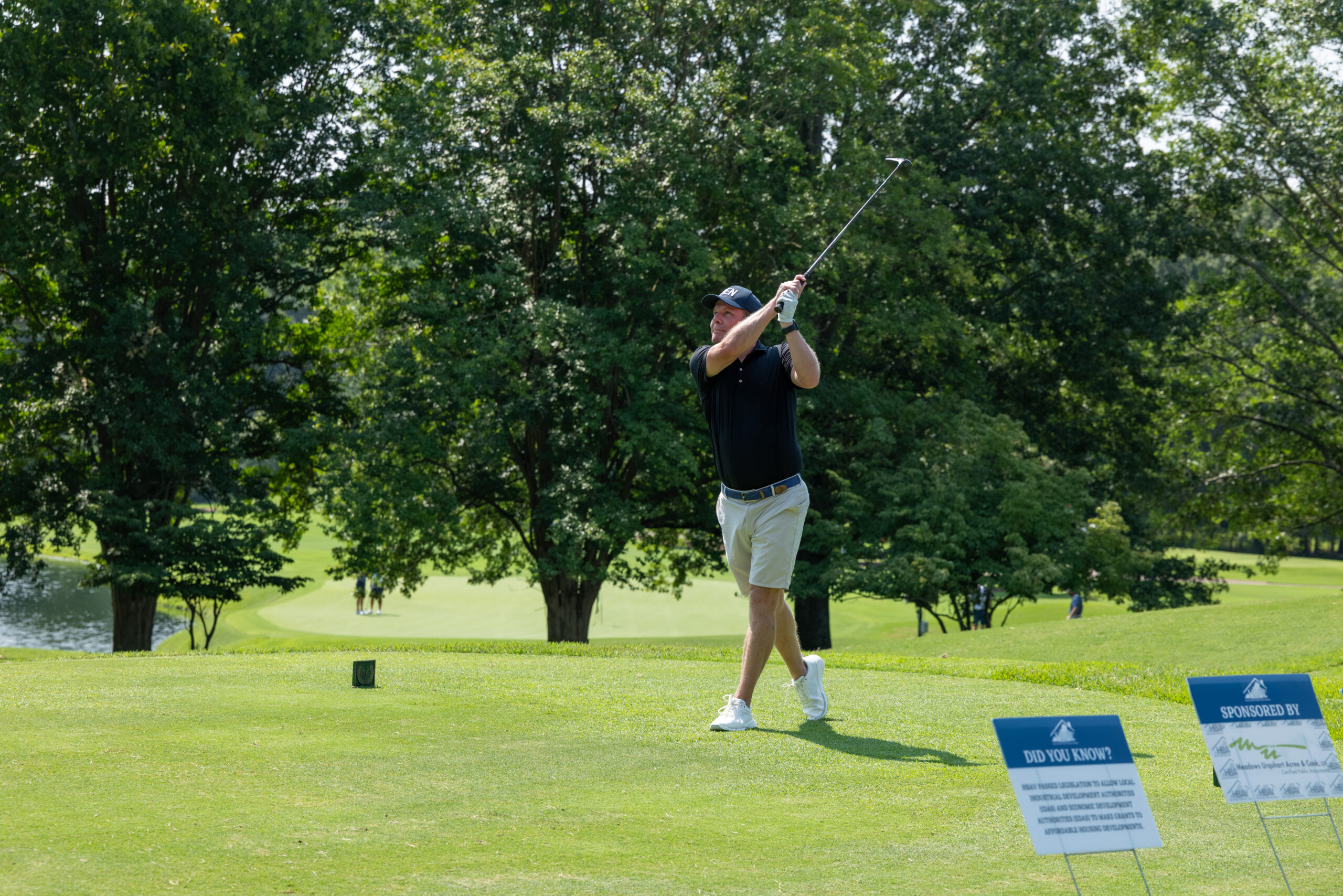 A man golfing and swinging his club at a tee box covered in grass clippings.