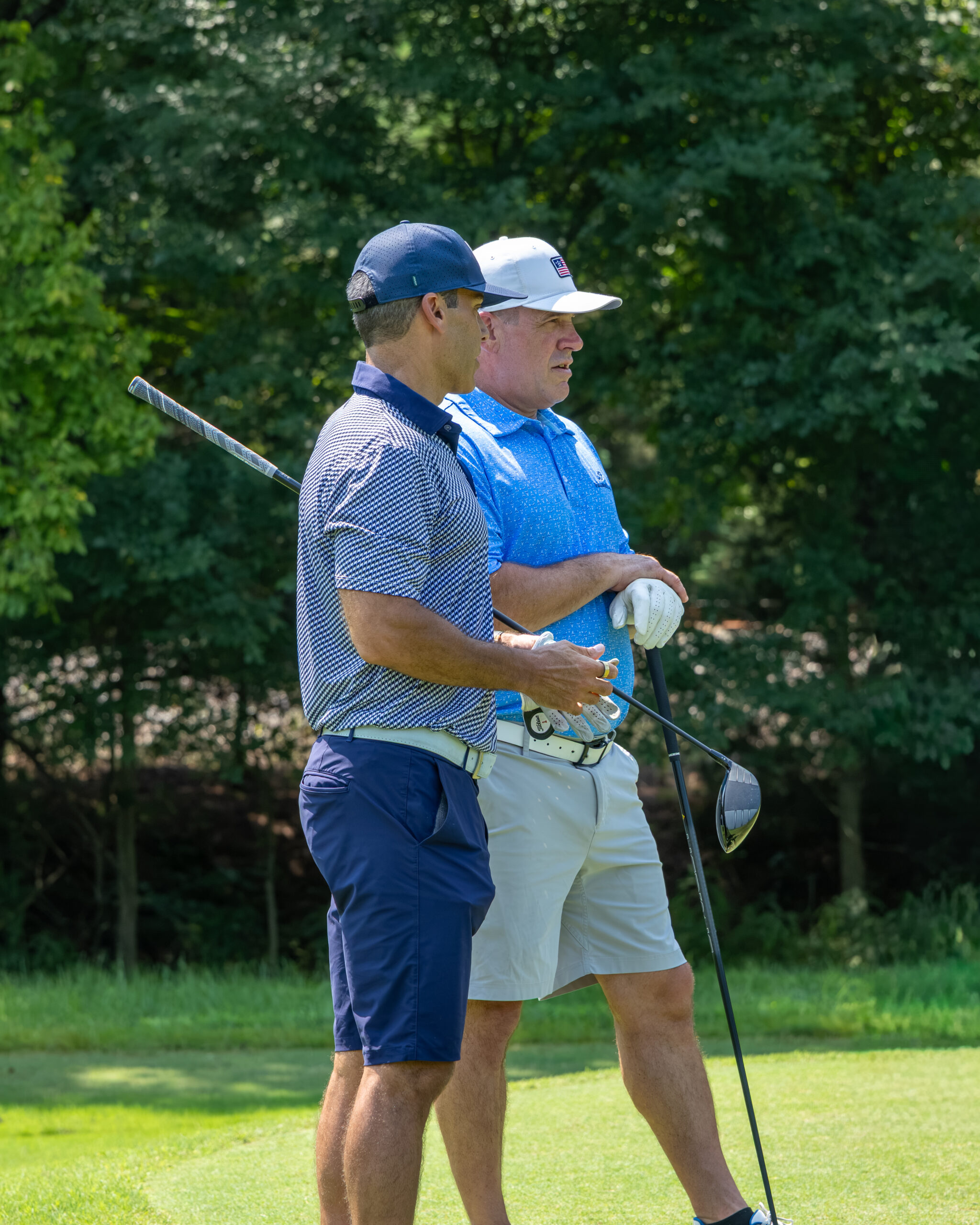 Two men on a golf course talking and looking at a golf ball.